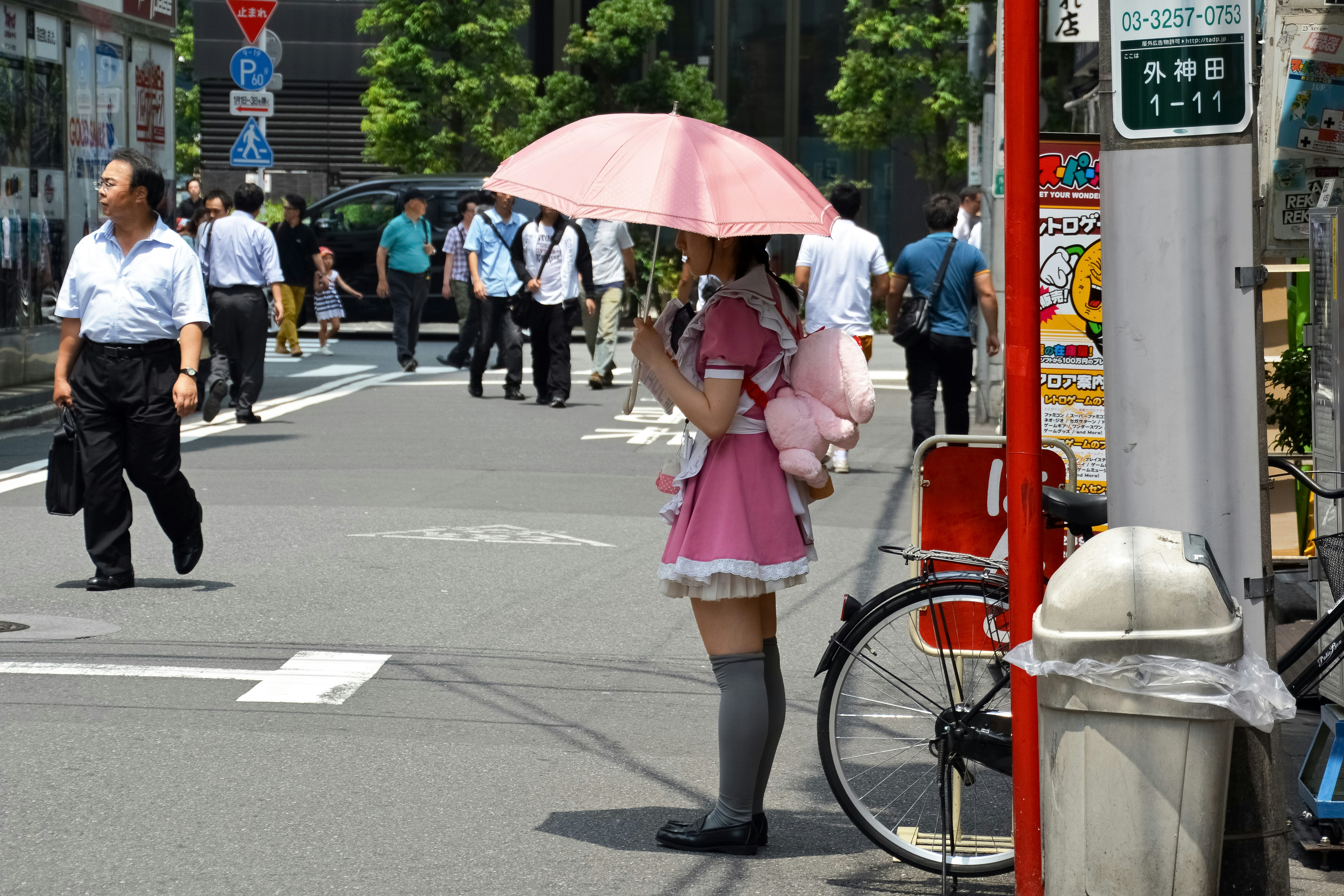 woman in pink dress holding pink umbrella walking on pedestrian lane during daytime